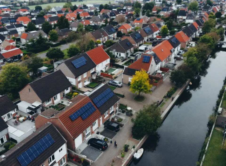 Een Nederlandse woonwijk van bovenaf, met zonnepanelen op veel daken en een gracht
